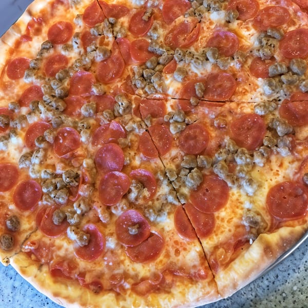 A close-up of a Little Anthony's pizza, topped with pepperoni and crumbled sausage.
